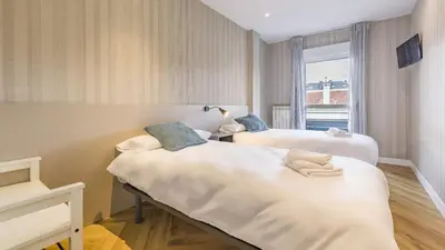 two beds in a room with a window at Pensión 9 de Abril in O Pedrouzo