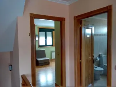 a bathroom with a toilet and a door to a room at A Lúa do Camiño in Melide