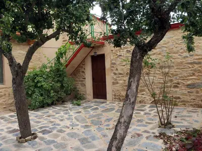 two trees in front of a building with a door at Mis antepasados in Murias de Pedredo
