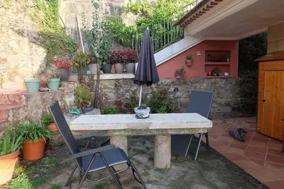 a stone table with two chairs and an umbrella at Casa Vallejo en Crecente in Crecíente