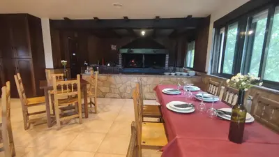 a dining room with a red table and chairs and a fireplace at Pension Parrilla Casa Vicente in Tineo