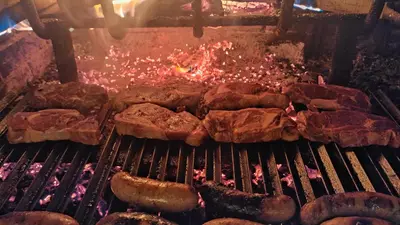 a group of meats and sausage on a grill at Pension Parrilla Casa Vicente in Tineo