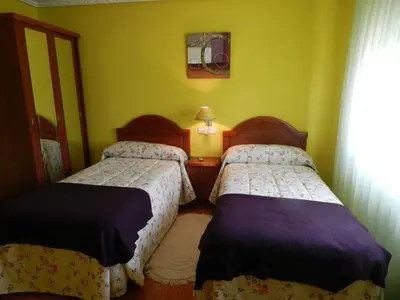 two beds in a room with green walls at Pension Parrilla Casa Vicente in Tineo