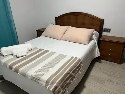 a bedroom with a bed with a wooden headboard at Universidad Piso Artur II in Ourense