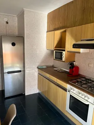 a kitchen with a stainless steel refrigerator and wooden cabinets at Universidad Piso Artur II in Ourense