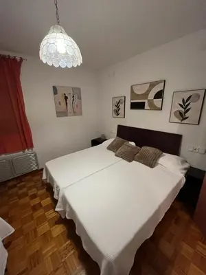 a bedroom with a large white bed and a chandelier at Dupléx en Estación de Manzaneda in Prada