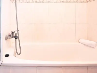 a white bath tub with a shower in a bathroom at Apartamento O Cobo Miño in Miño