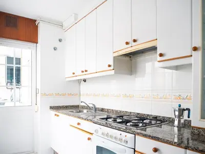 a white kitchen with white cabinets and a sink at Apartamento O Cobo Miño in Miño