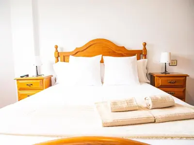 a bedroom with a white bed with two night stands at Apartamento O Cobo Miño in Miño