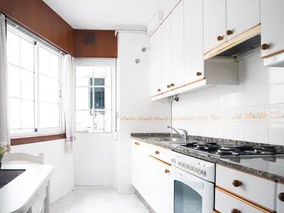 a kitchen with white cabinets and a sink at Apartamento O Cobo Miño in Miño