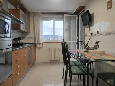a kitchen with a table and chairs and a window at Con vistas al puente del Milenio y plaza de garaje in Ourense