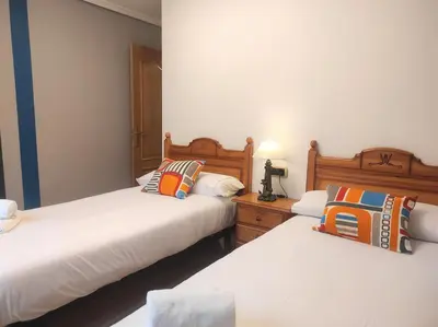 two beds in a room with white walls at Con vistas al puente del Milenio y plaza de garaje in Ourense