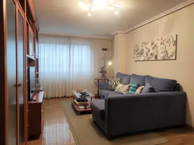 a living room with a blue couch and a television at Con vistas al puente del Milenio y plaza de garaje in Ourense