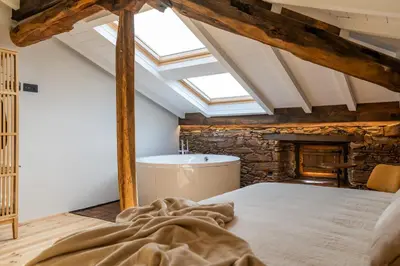 an attic bedroom with a bed and a bath tub at A Rectoral de Seadur in Seadur