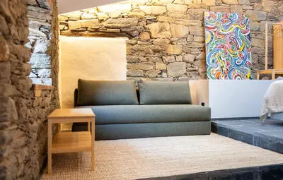 a blue couch in a room with a stone wall at A Rectoral de Seadur in Seadur