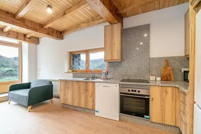 a kitchen with wooden cabinets and a stove and a chair at Casa de montaña - A Palleira do Curralón in Pradoalvar
