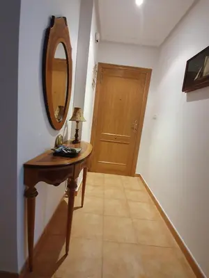 a hallway with a wooden table and a mirror at A menos de doscientos metros de la playa in Foz