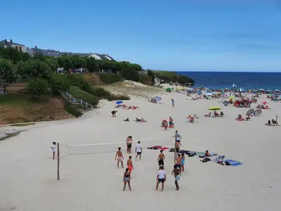 a group of people playing volleyball on a beach at A menos de doscientos metros de la playa in Foz