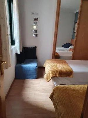 a small room with two beds and a blue chair at A menos de doscientos metros de la playa in Foz