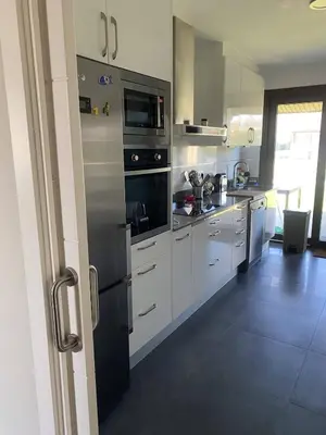 a kitchen with white cabinets and a black refrigerator at Casa do alpendre in Ourense