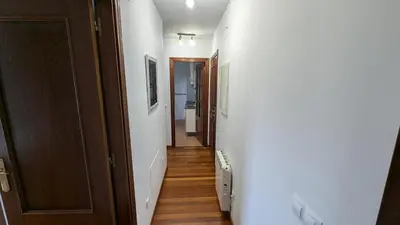 a hallway with white walls and wooden floors and a door at Alojamiento La Caridad in La Caridad