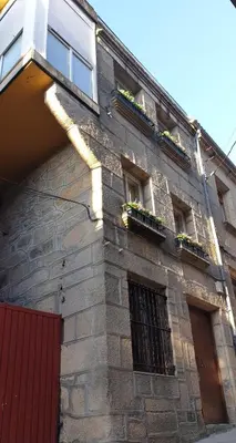 a brick building with windows and potted plants on it at Abacería in Allariz