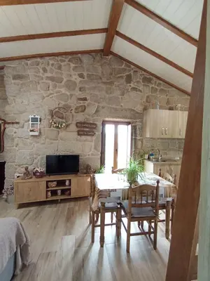 a kitchen with a table and a stone wall at A Feitiña de Rubiacós in Rubiacós