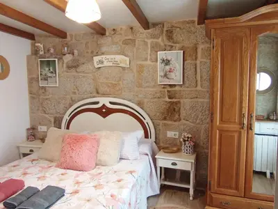 a bedroom with a bed and a stone wall at A Feitiña de Rubiacós in Rubiacós