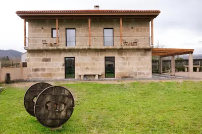 a large stone building with a bench in front of it at La Molinera Casa Rural - Ribeira Sacra in Ourense