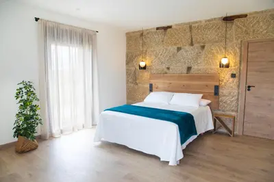 a bedroom with a large bed and a brick wall at La Molinera Casa Rural - Ribeira Sacra in Ourense