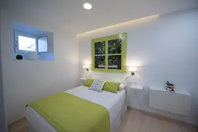a bedroom with a bed with green sheets and a window at Bolboreta Apartments by Como en Casa in Santiago de Compostela