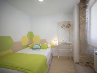a bedroom with a bed with green and yellow sheets at Bolboreta Apartments by Como en Casa in Santiago de Compostela
