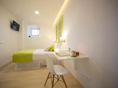 a white bedroom with a bed and a desk with a chair at Bolboreta Apartments by Como en Casa in Santiago de Compostela