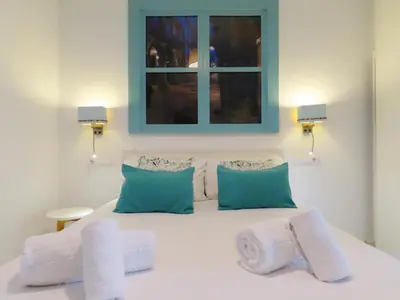 a bedroom with a white bed with blue accents at Bolboreta Apartments by Como en Casa in Santiago de Compostela