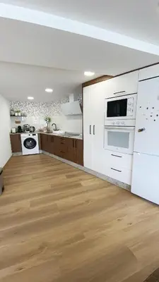 a kitchen with white appliances and a wooden floor at Gallaecia Dúplex in Arzúa