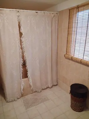 a bathroom with a shower curtain and a tiled floor at Casa Engracia in Arcos