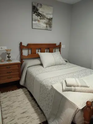 a bedroom with a bed with a wooden headboard and a table at Casa Engracia in Arcos