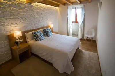 a bedroom with a bed and a stone wall at Casa Juancito in Santiago de Compostela