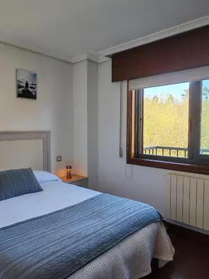 a bedroom with a bed and a large window at Apartamento Ó Xeitoso Milladoiro in Milladoiro