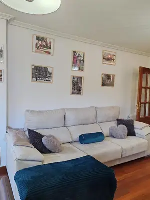 a white couch in a living room with pictures on the wall at Apartamento Ó Xeitoso Milladoiro in Milladoiro