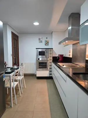 a large kitchen with a counter and a table at Apartamento Ó Xeitoso Milladoiro in Milladoiro
