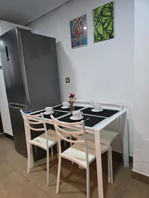 a kitchen with a table and chairs and a refrigerator at Apartamento Ó Xeitoso Milladoiro in Milladoiro