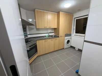 a kitchen with wooden cabinets and a washing machine at Oktheway O Burgo in El Burgo