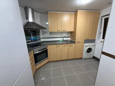a kitchen with wooden cabinets and a washer and dryer at Oktheway O Burgo in El Burgo