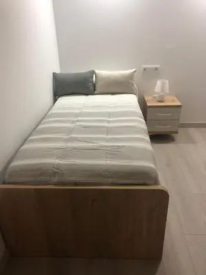 a large bed in a room with a night stand at Apartamentos Playa Frejulfe in Paderne