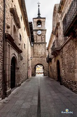 an alley with a clock tower in an old building at Apartamento nuevo casco antiguo in Ponferrada