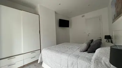 a white bedroom with a bed and a tv at Apartamento nuevo casco antiguo in Ponferrada