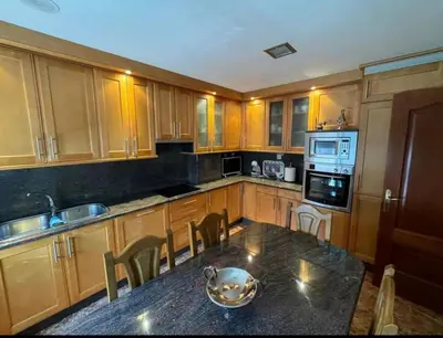 a kitchen with wooden cabinets and a table with a bowl on it at casa habana in Carballino