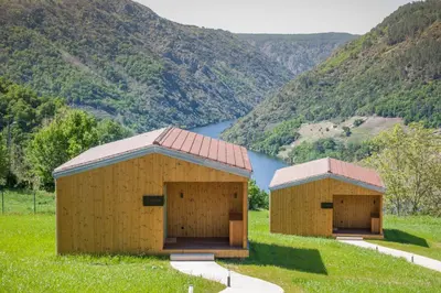 two sheds in a field with a mountain at Cabañas Ribeira Sacra in Parada del Sil