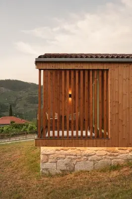 a wooden building with two benches in a field at Cabañas Ribeira Sacra in Parada del Sil